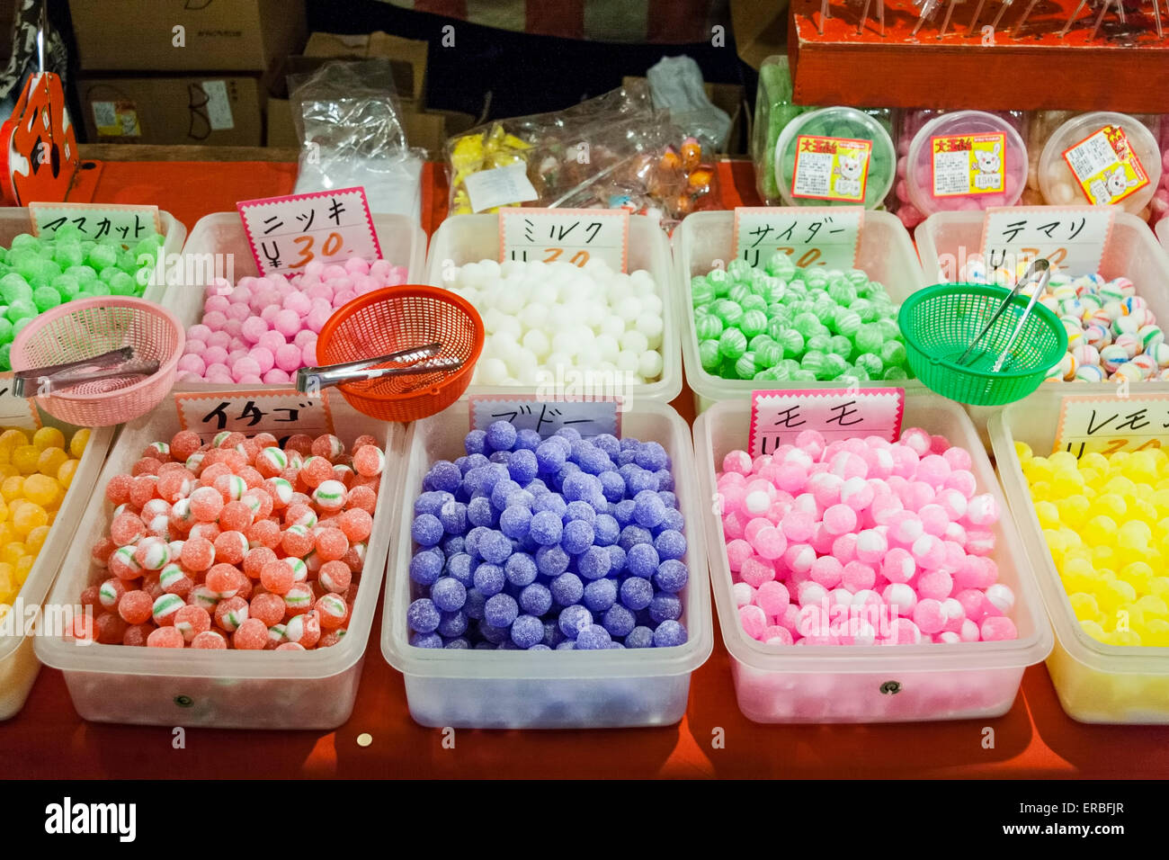 Bandejas de plástico de dulces de colores diferentes en el mercado japonés  se estancan por la noche. Cestas de pesaje pequeñas con pinzas en la parte  superior para uso de los clientes