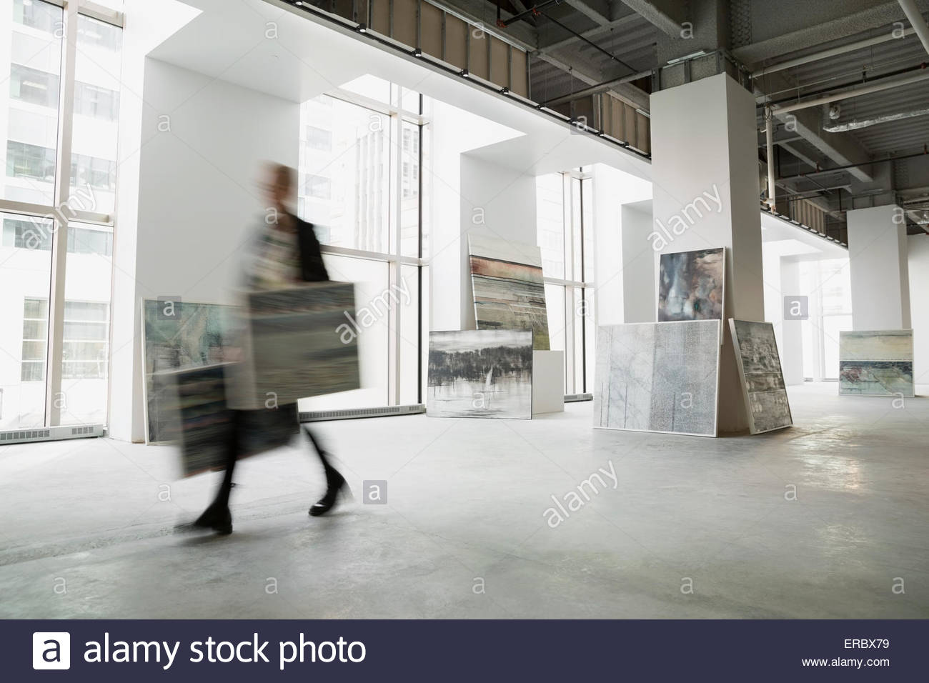 Marchante de Arte caminando con pinturas en galería de arte Foto de stock