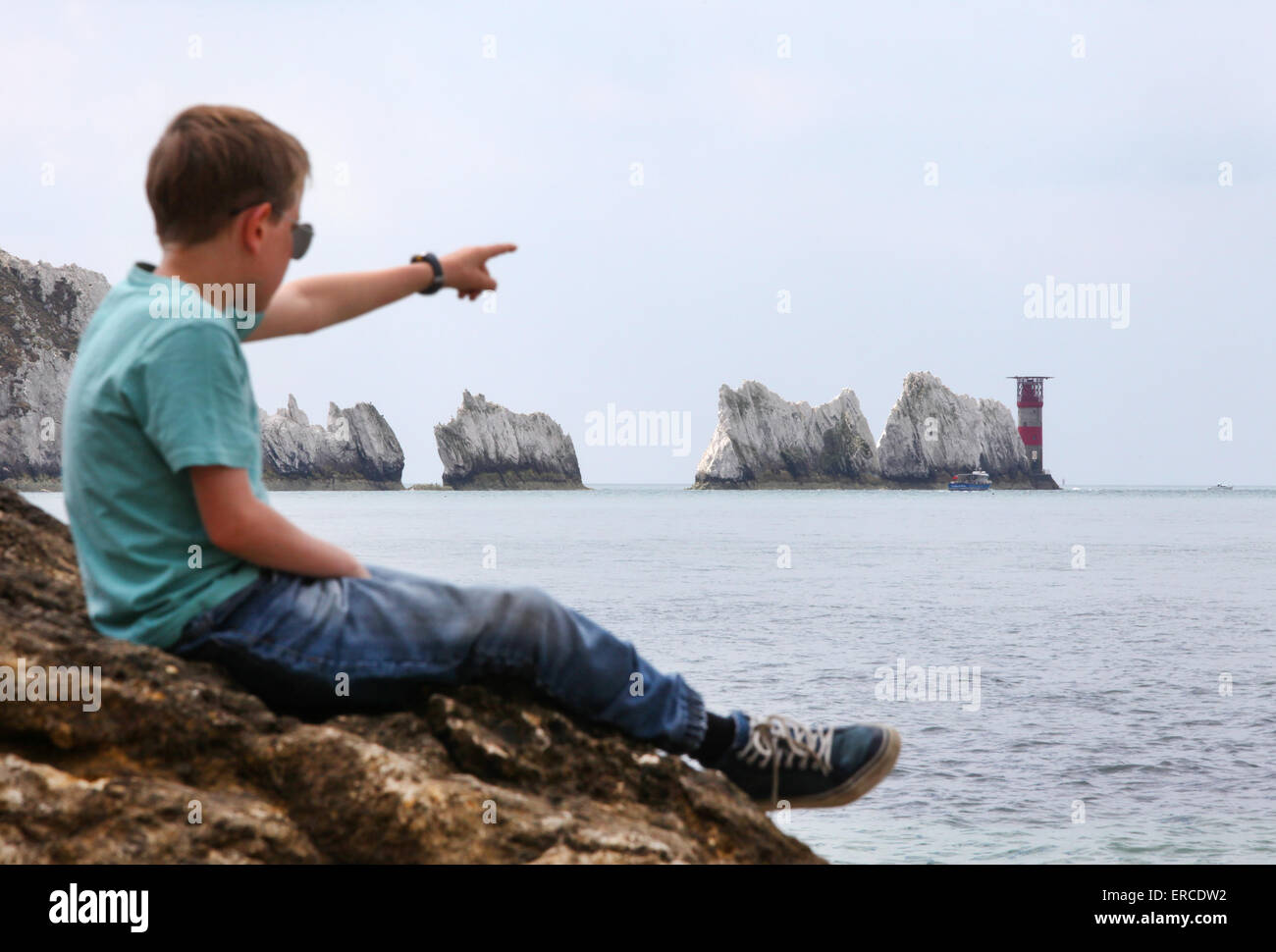 Un muchacho en una roca, disfrutando de la vista en las agujas en la Isla de Wight (punto de enfoque sobre las agujas) Foto de stock