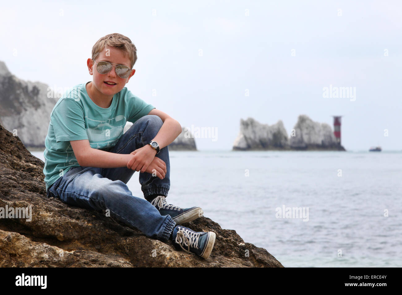 Un muchacho en una roca, disfrutando de la vista en las agujas en la Isla de Wight Foto de stock