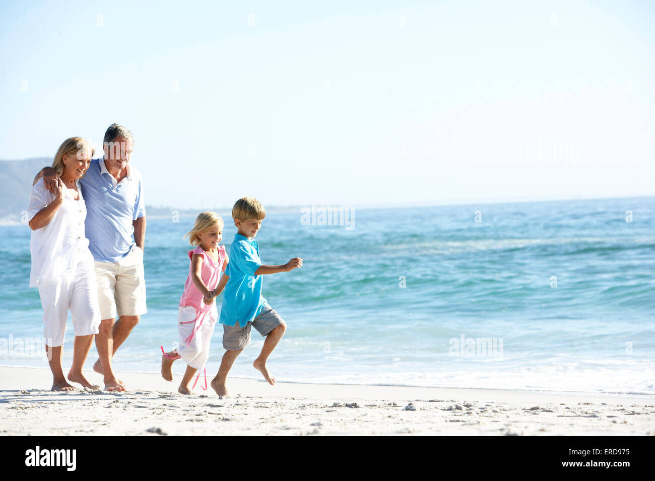 Abuelos y nietos caminando por la playa Foto de stock