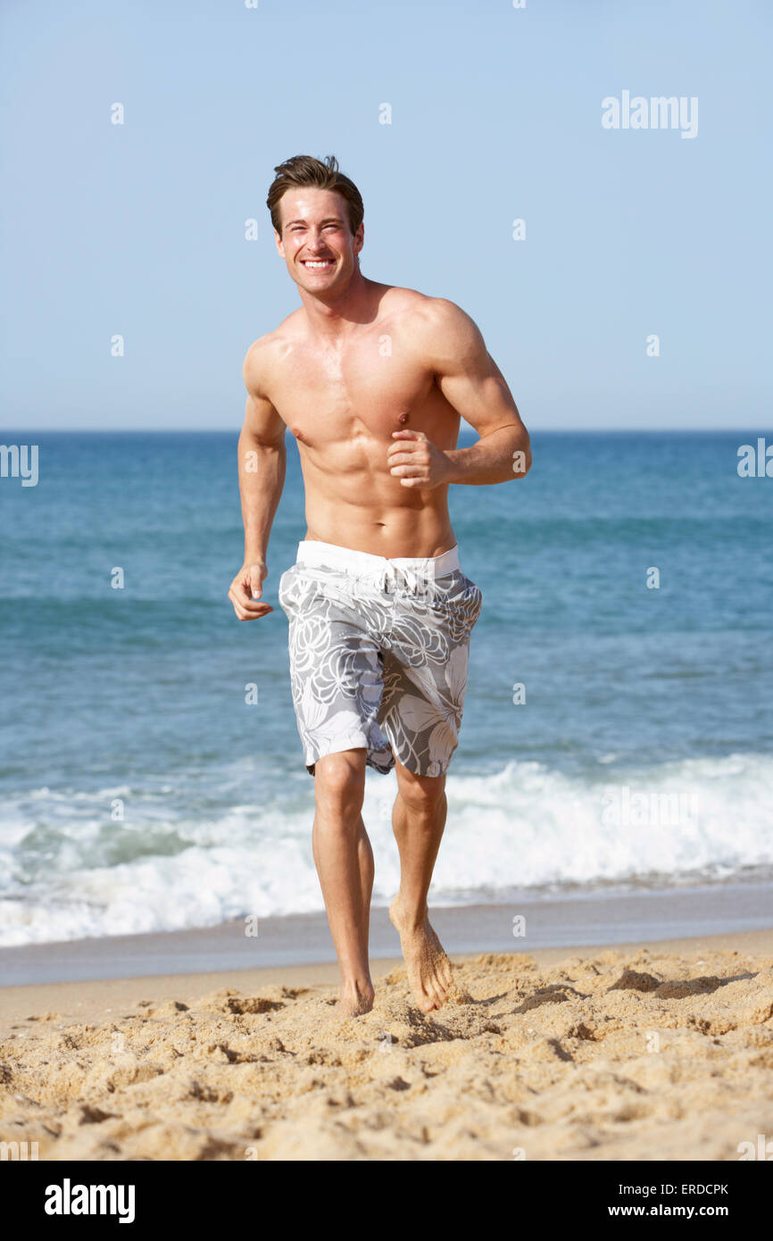 Tipo delantero Lo dudo Optimismo Joven hombre vestido con traje de baño corriendo junto a la playa  Fotografía de stock - Alamy