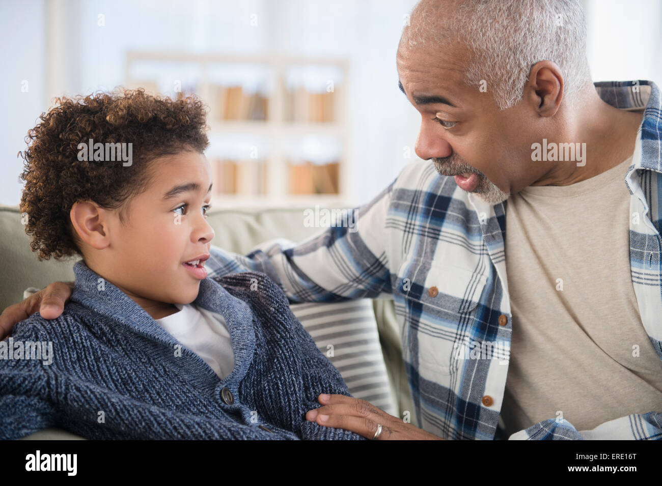 Raza mixta, abuelo y nieto hablando en el sofá Foto de stock