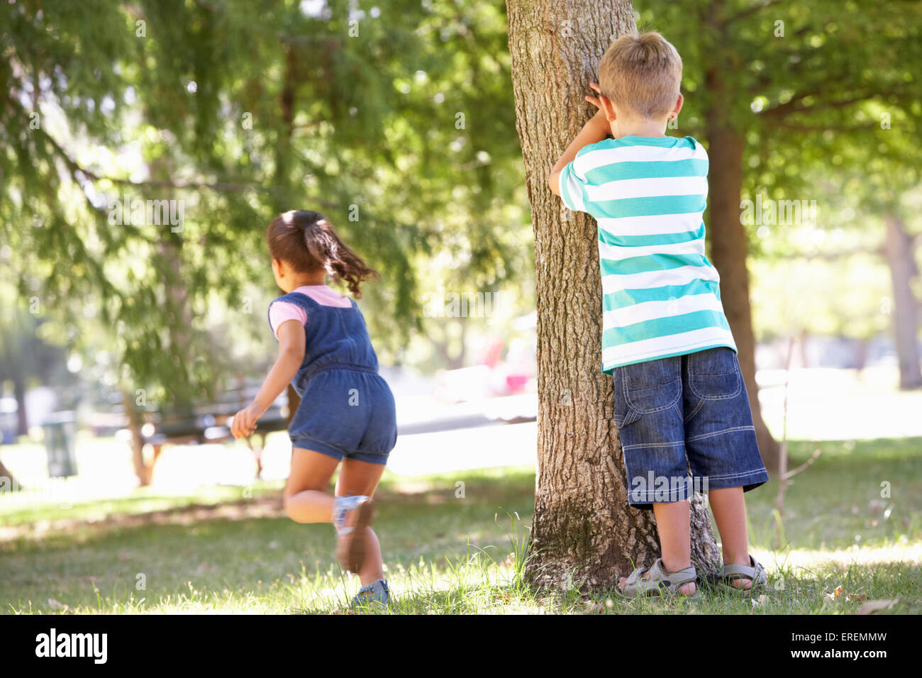 Dos niños jugando al escondite en el parque Foto de stock