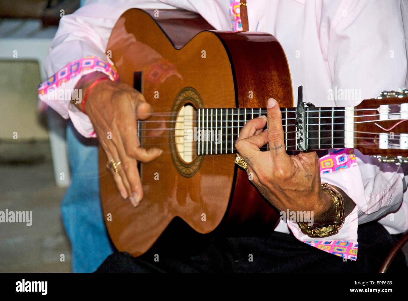 Detalle de manos del guitarrista gitano tocando la guitarra flamenca. La  atención se centra más en la mano izquierda, que es un acorde digitado en  el cuello. Un capodastro está colocado en