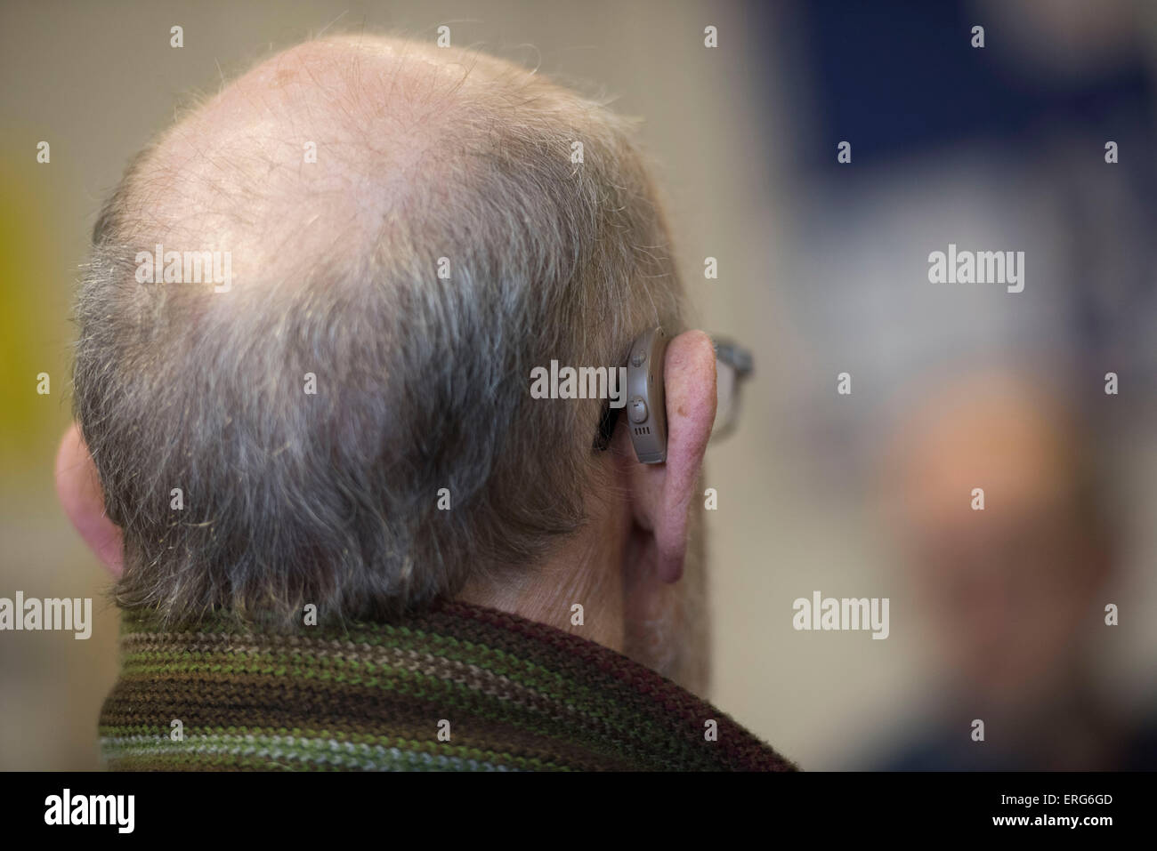 Un jubilado con problemas de audición que usa un audífono. Foto de stock