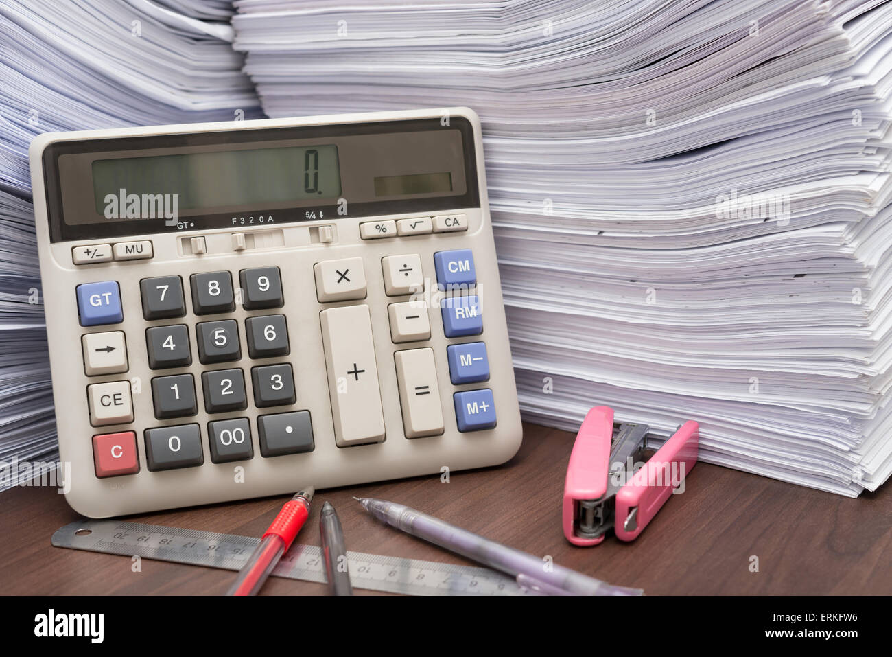 Montón de documentos sobre el escritorio apilar alto con calculadora y lápiz regla en la oficina Foto de stock