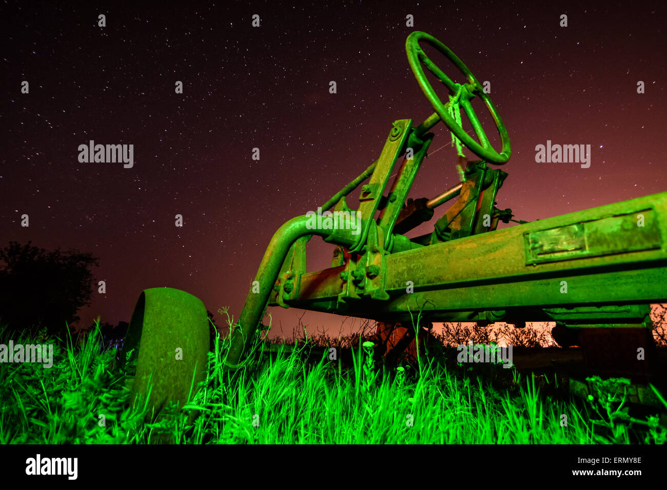 Correr del tiempo concepto - viejo tractor oxidado en la noche estrellada a luz inusual Foto de stock