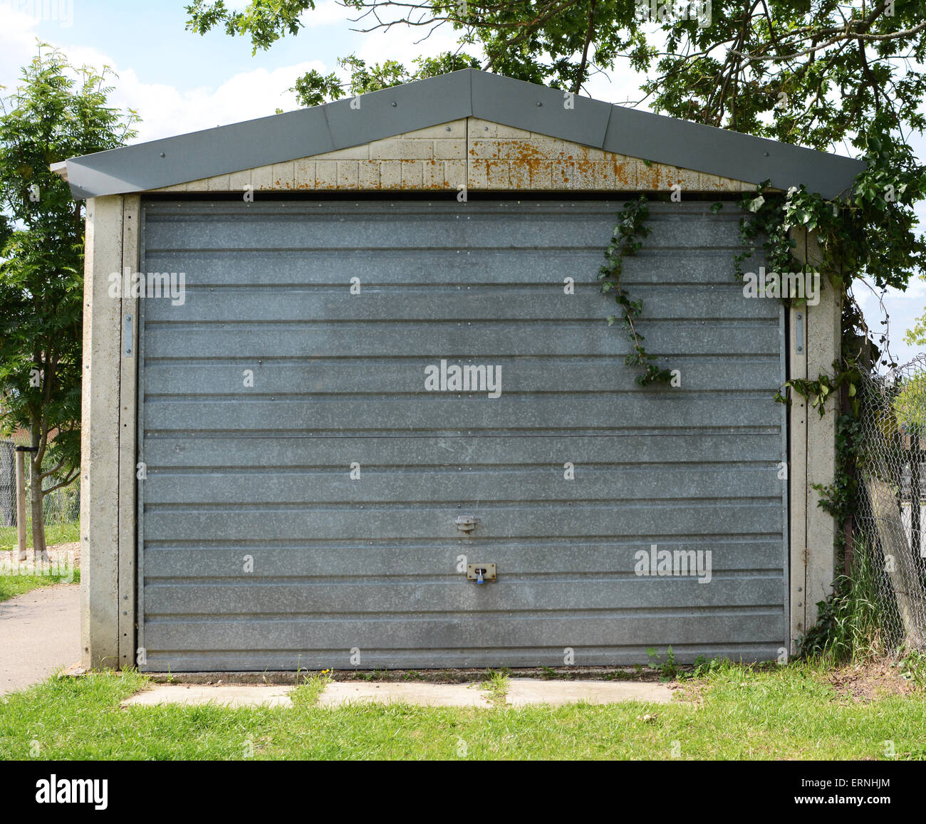 Garaje independiente con un bloqueado, puerta metálica sin pintar, cubierto  de hiedra Fotografía de stock - Alamy