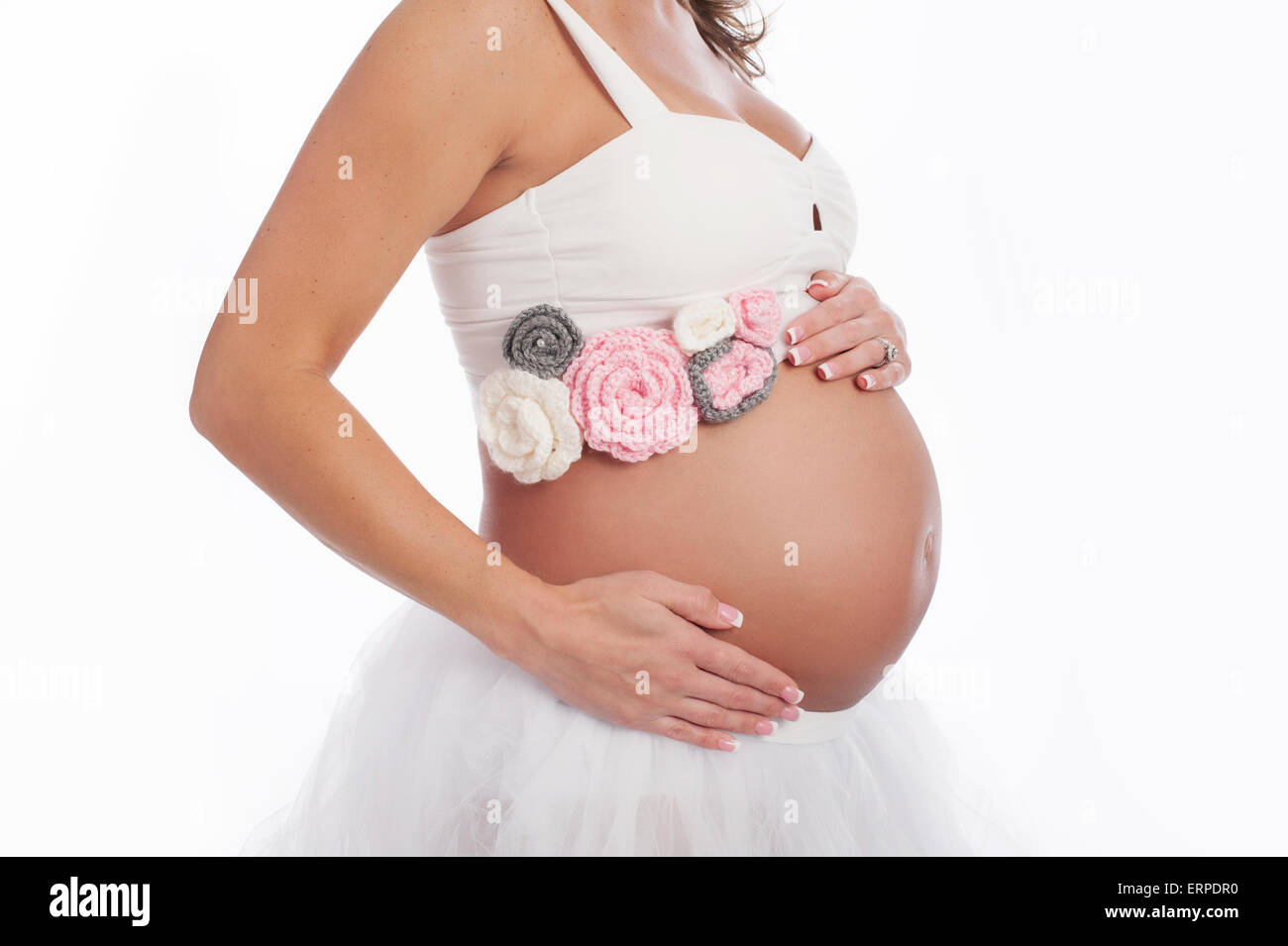 Un cierre para arriba, vista lateral de una mujer embarazada vientre. Ella lleva una cosecha superior, tul blanco falda y un ganchillo rosa, gris Fotografía de stock - Alamy