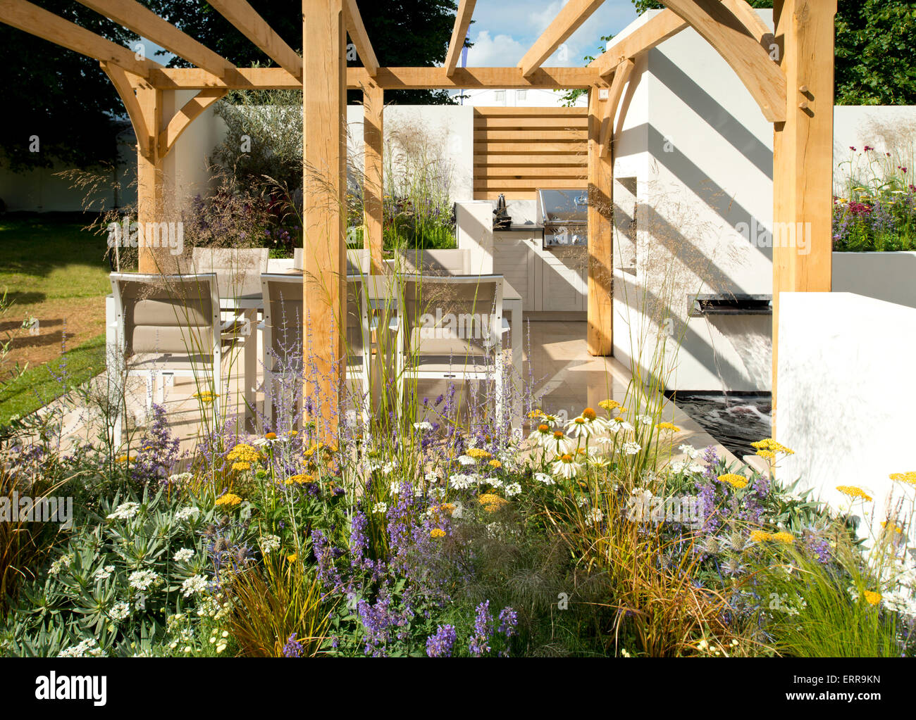 Una mesa de comedor y sillas en una cocina al aire libre bajo una pérgola en el jardín al aire libre en el Hampton Court Flower Show 2014 Foto de stock