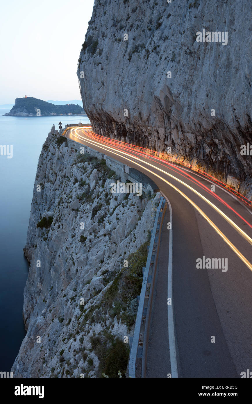Exposición en el tiempo de los coches que pasan en una cornisa al crepúsculo. Capo Noli, Provincia de Savona, Liguria, Italia. Foto de stock