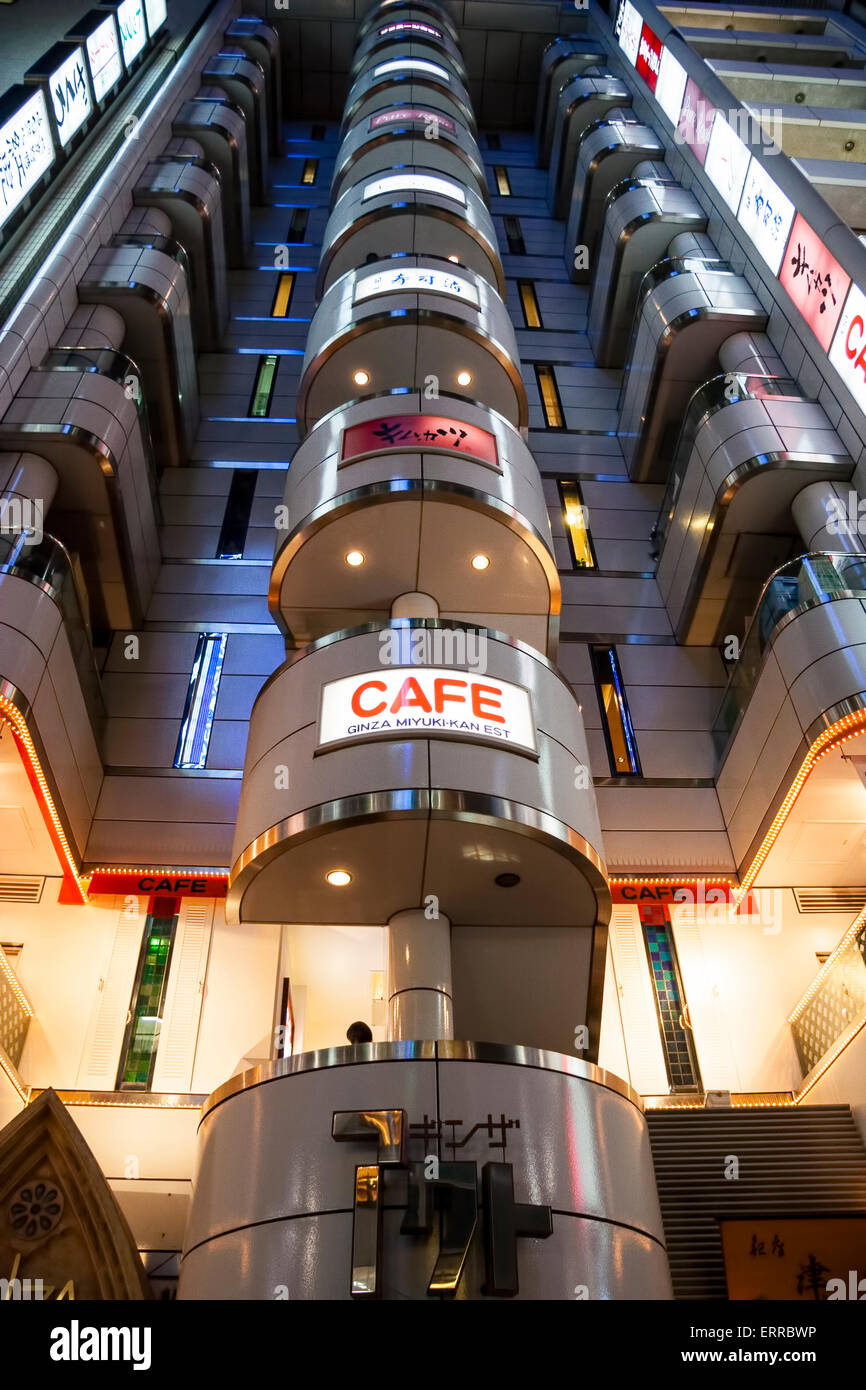 El Café de Ginza Miyuki-kan en la distintiva forma de la fachada W del edificio Ginza Act en Tokio por la noche. Vista de ángulo bajo mirando hacia el edificio. Foto de stock