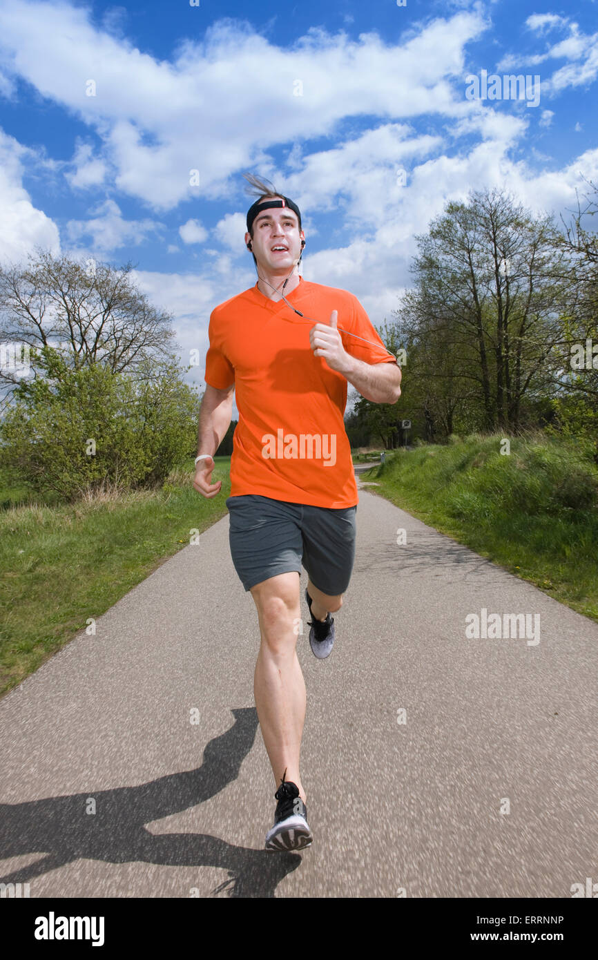 Frontal vista completa del cuerpo de un hombre joven en la vestimenta  deportiva sobre el asfalto corriendo hacia la cámara Fotografía de stock -  Alamy