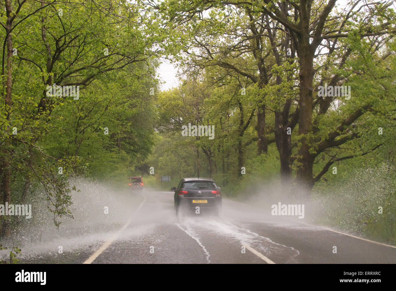 Alquiler de salpicaduras a través de grandes charcos en el país por carretera en Escocia tras la intensa lluvia Foto de stock