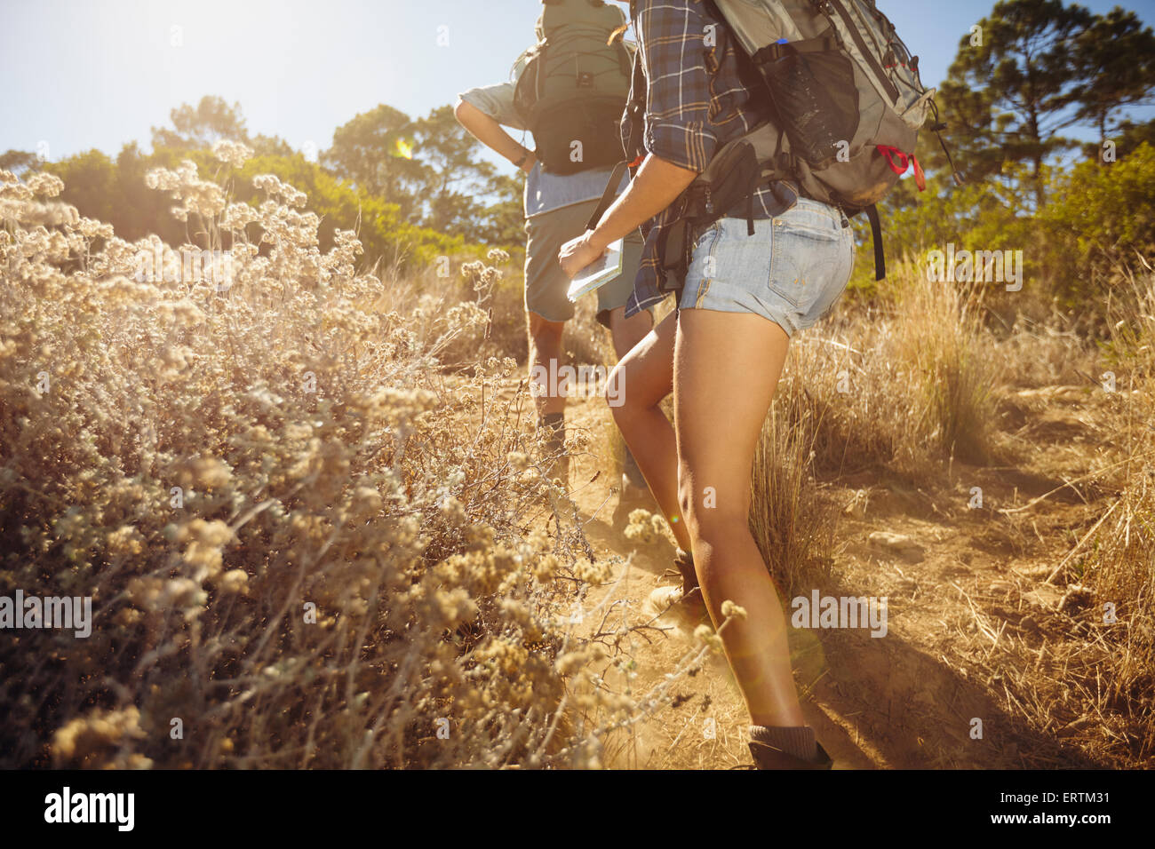 Imagen recortada de un hombre y una mujer caminando en el país ruta trail. Pareja joven senderismo en la montaña en día soleado. Foto de stock