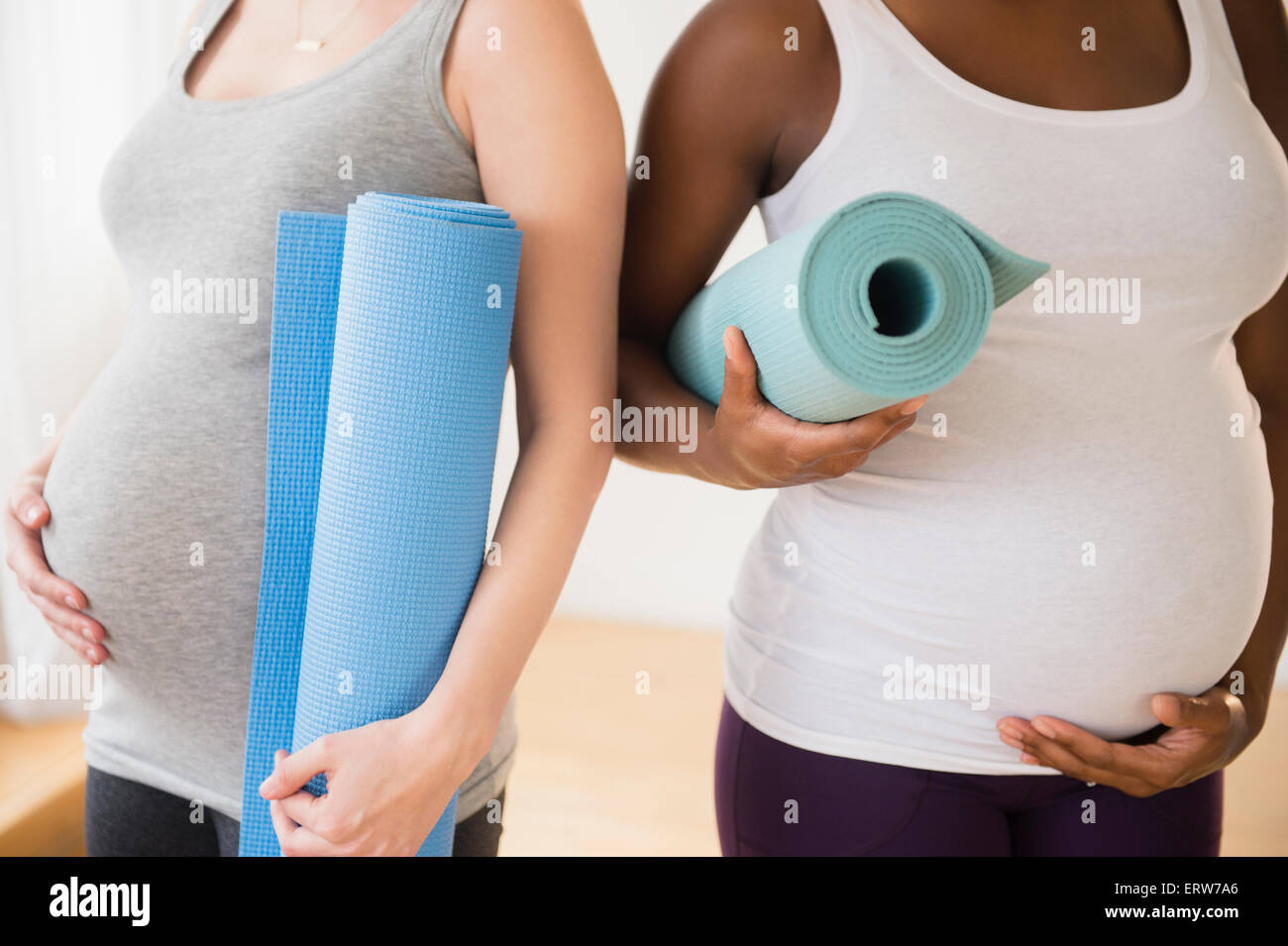 Embarazadas portadoras de las esteras del yoga Foto de stock