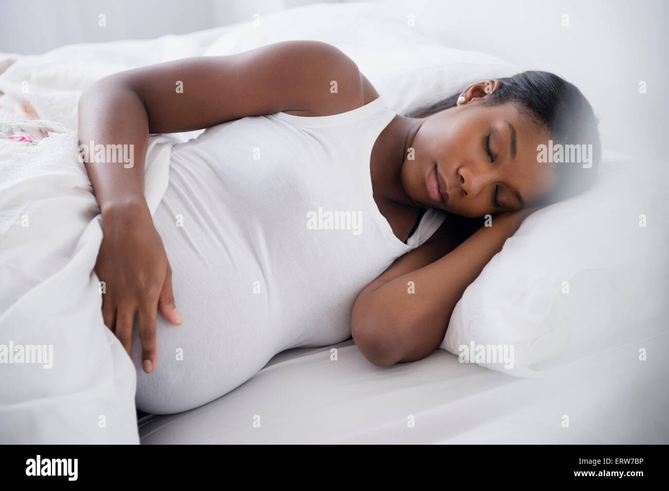 Mujer embarazada negro durmiendo en cama Foto de stock