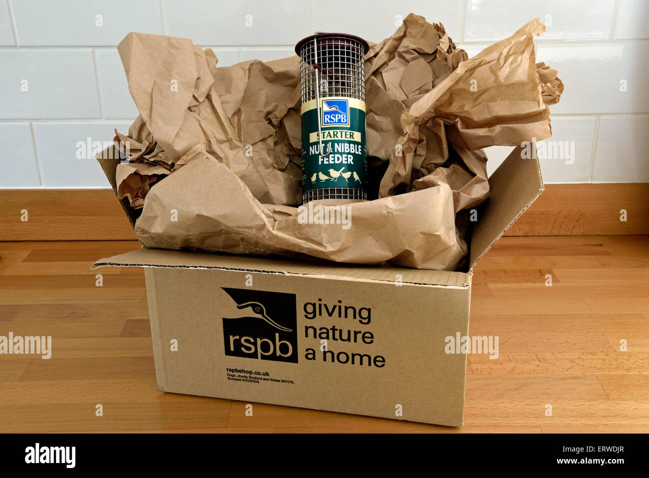 Alimentador de las aves RSPB envuelto en tres hojas de papel marrón dentro de una caja de cartón, pero el exceso de embalaje sostenible, cero residuos. Foto de stock