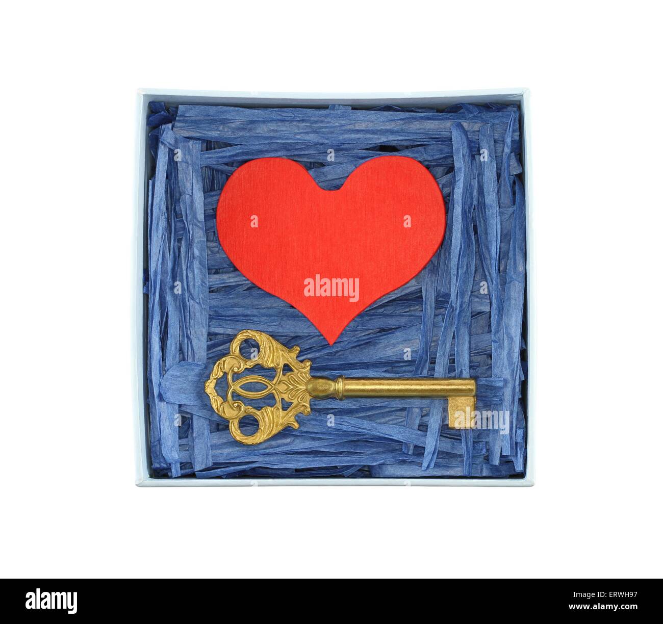 Corazón de madera pintadas de rojo y bronce clave encerrada con papel azul tiras de rafia en el cuadro azul claro aislado sobre fondo blanco. Foto de stock