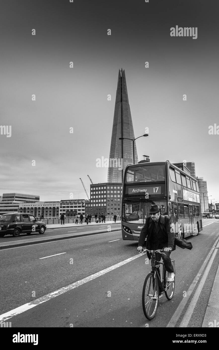 Ciclista cruzando el puente de Londres en moto con el casco en el fondo, Londres, Reino Unido. Foto de stock