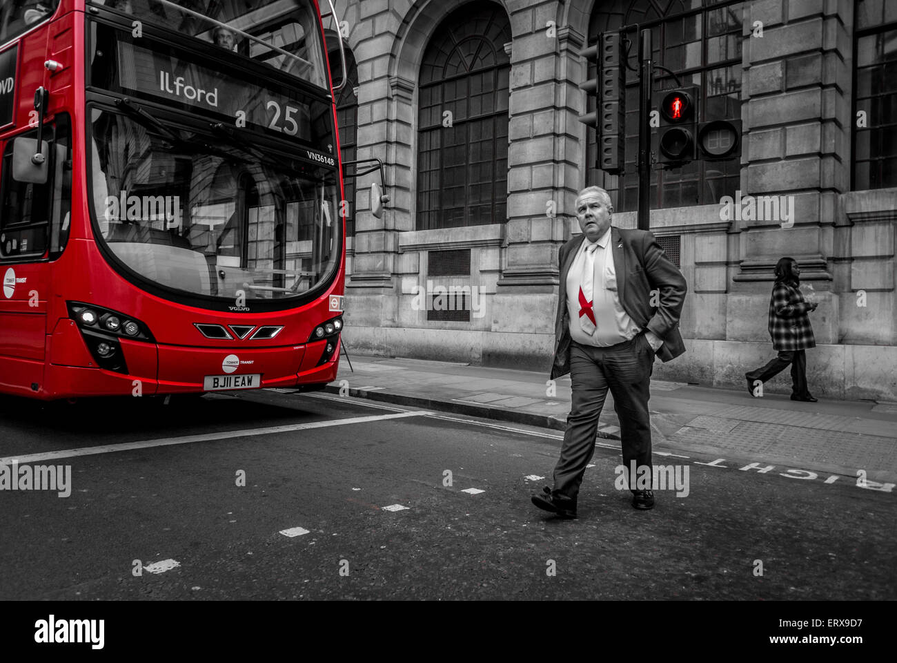 Empresario con corbata bandera inglesa crossing road en frente de red double decker bus, Londres, Reino Unido. Foto de stock