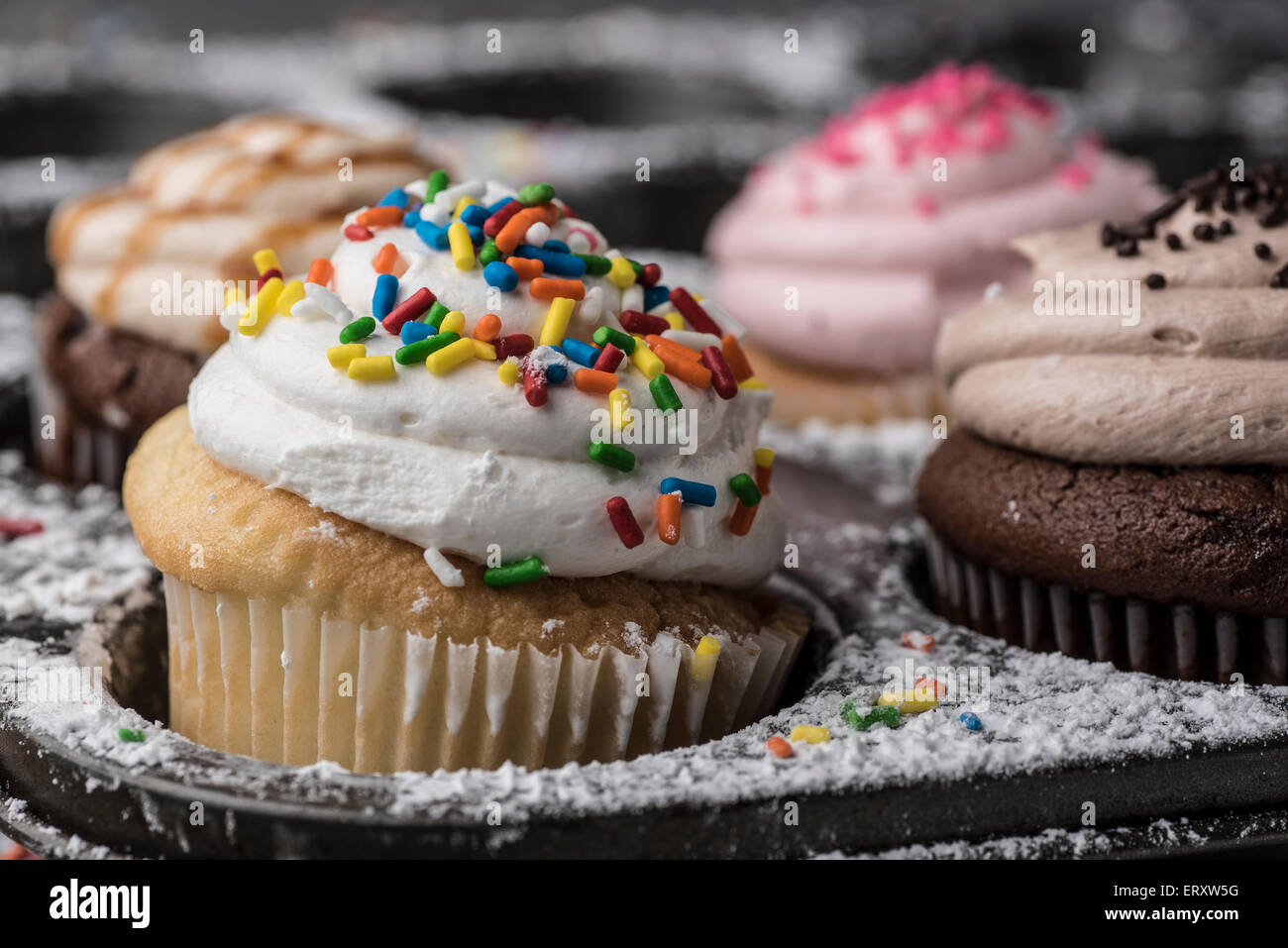 Un colorido cupcake rodeado por azúcar y espolvorea Foto de stock