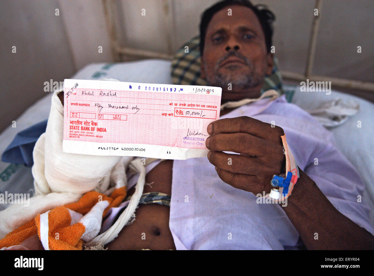 Abdul Rashid mostrando una indemnización verificar víctima de un ataque terrorista por Deccan Muyahidín en Bombay Bombay Foto de stock