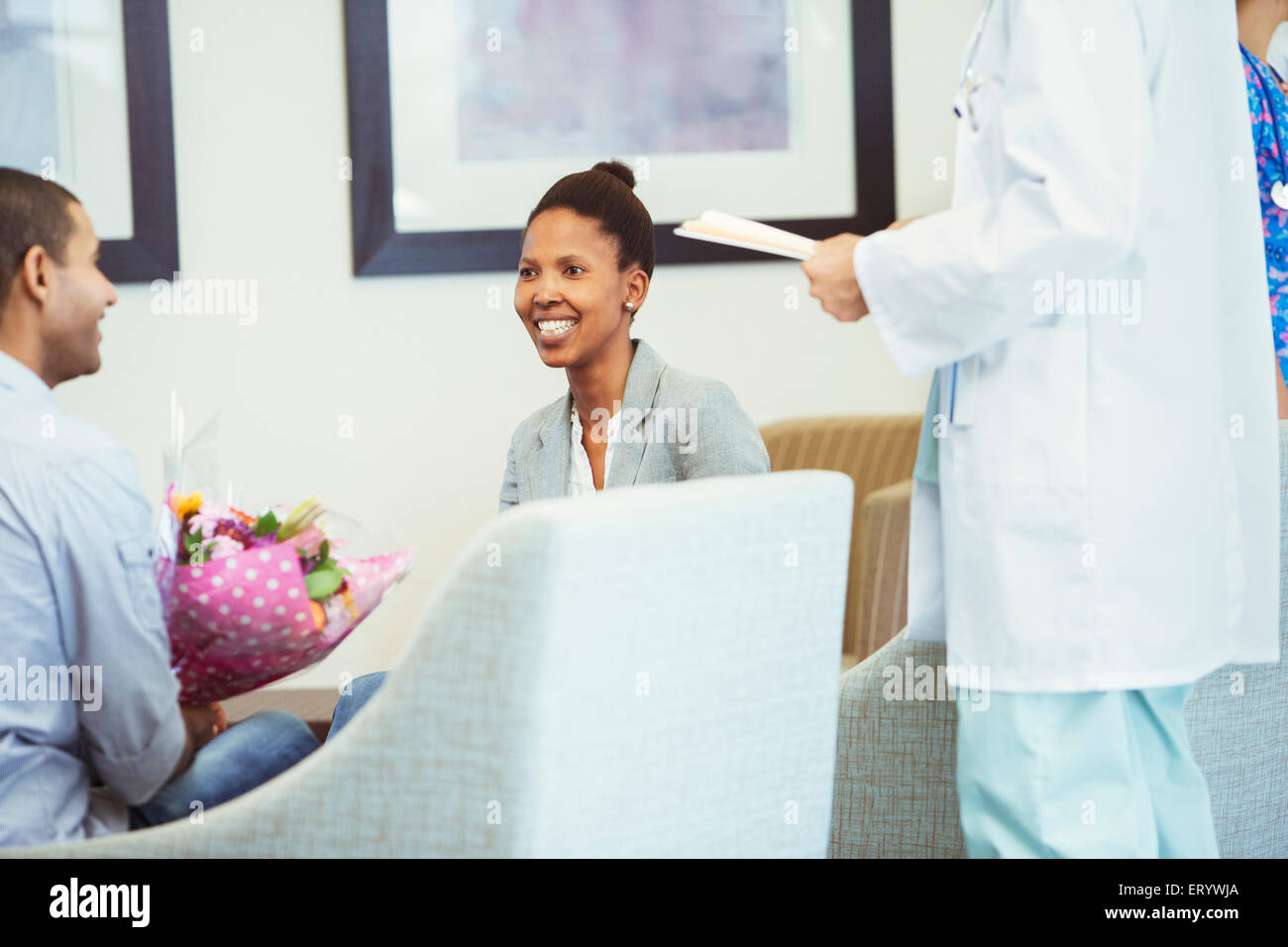 Reunión con el doctor pareja sonriente en la sala de espera del hospital Foto de stock