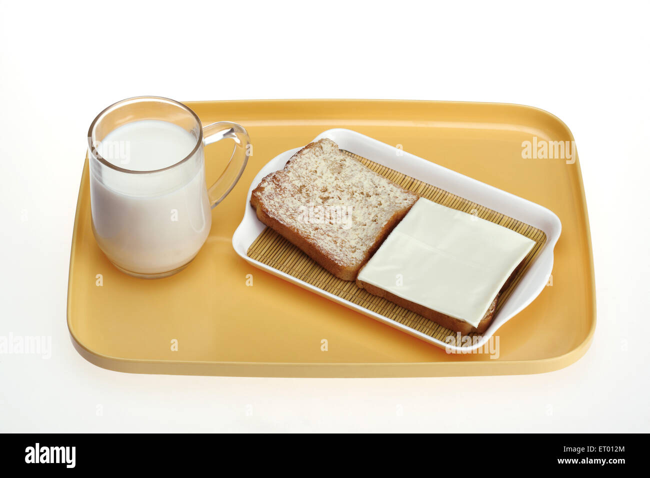Taza de leche con tostadas de pan con mantequilla para untar y la rodaja de queso Foto de stock