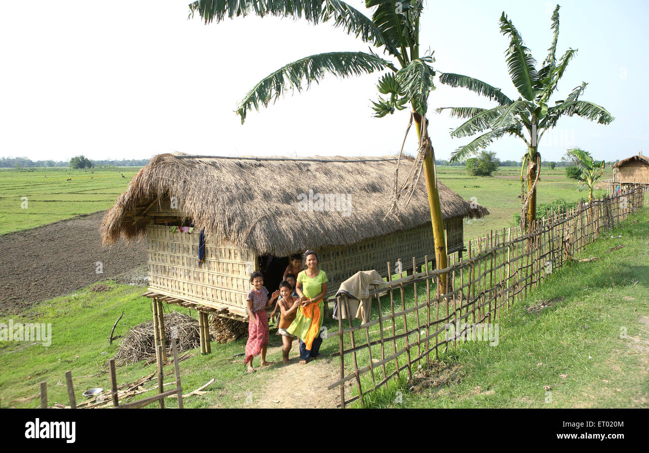 Familia delante de cabañas de bambú en la isla de majuli Assam India NOMR ; ; Foto de stock
