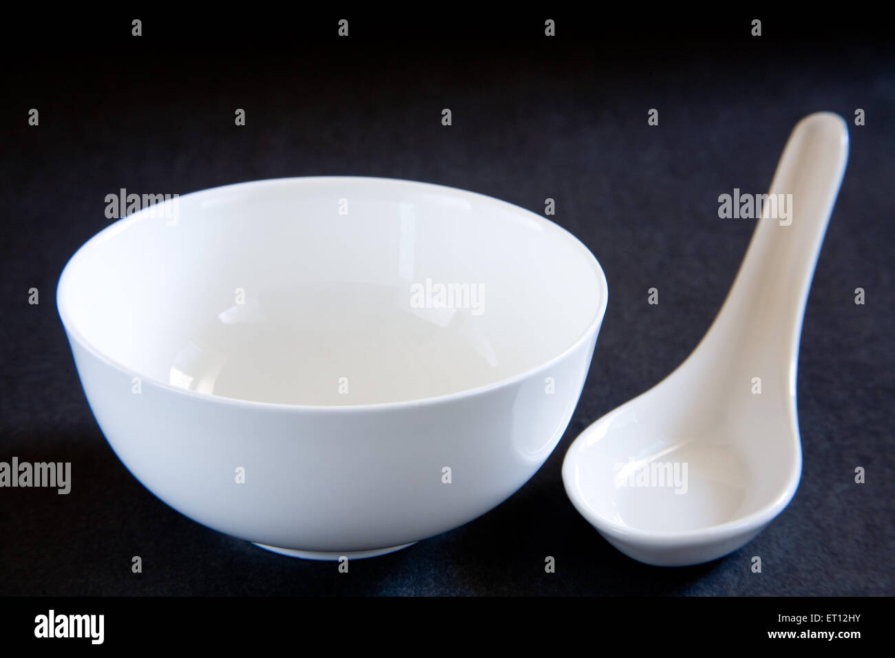 tazón redondo de cerámica cuchara blanca fondo negro Foto de stock
