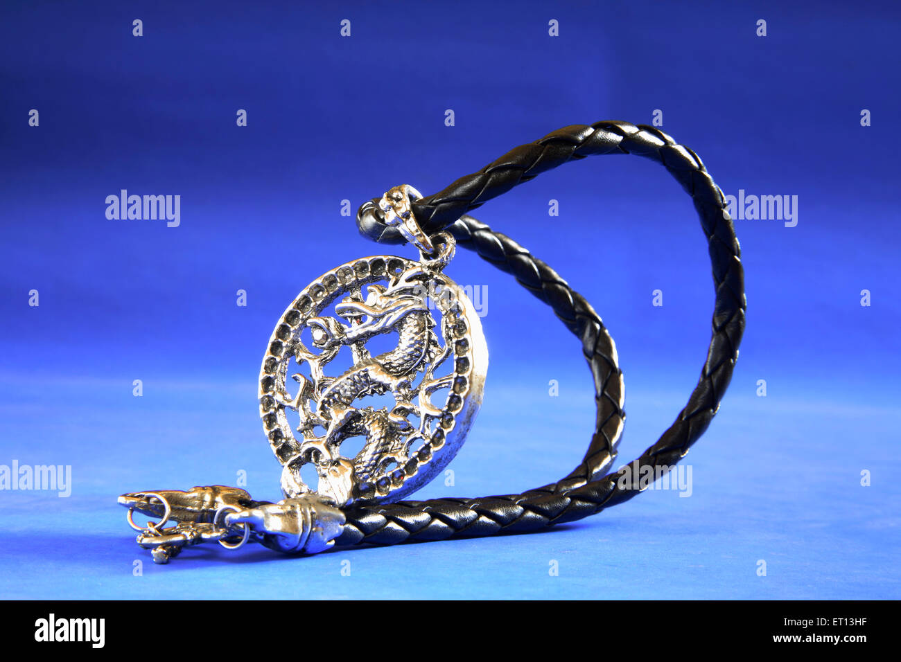 Colgante collar amuleto con diseño de dragón chino sobre fondo azul Foto de stock