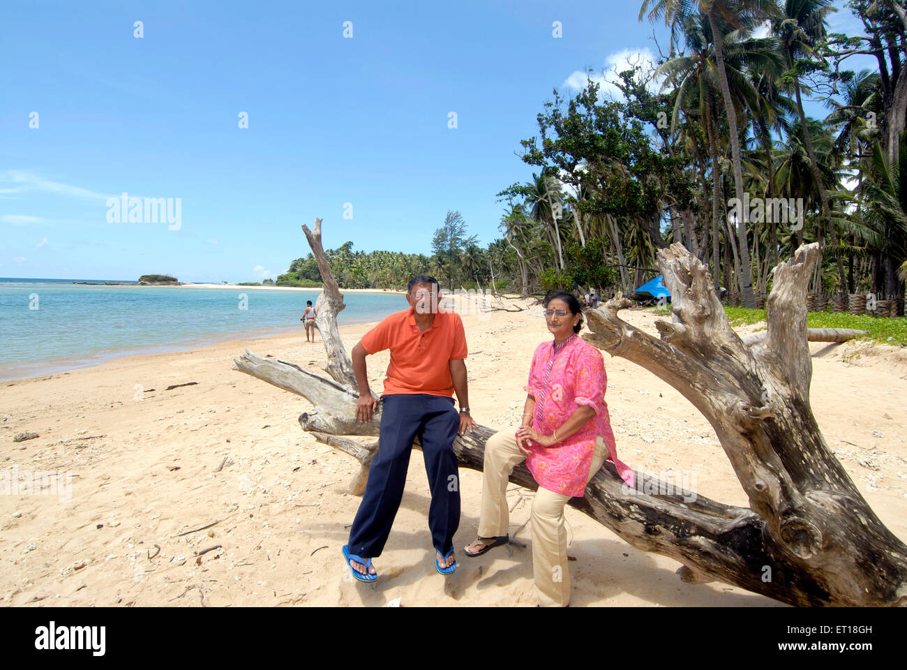 Viejo hombre y mujer sentada sobre un tronco en la playa de Radhanagar ; Havelock ; Las Islas de la Bahía de Bengala; Islas de Andaman y Nicobar Foto de stock