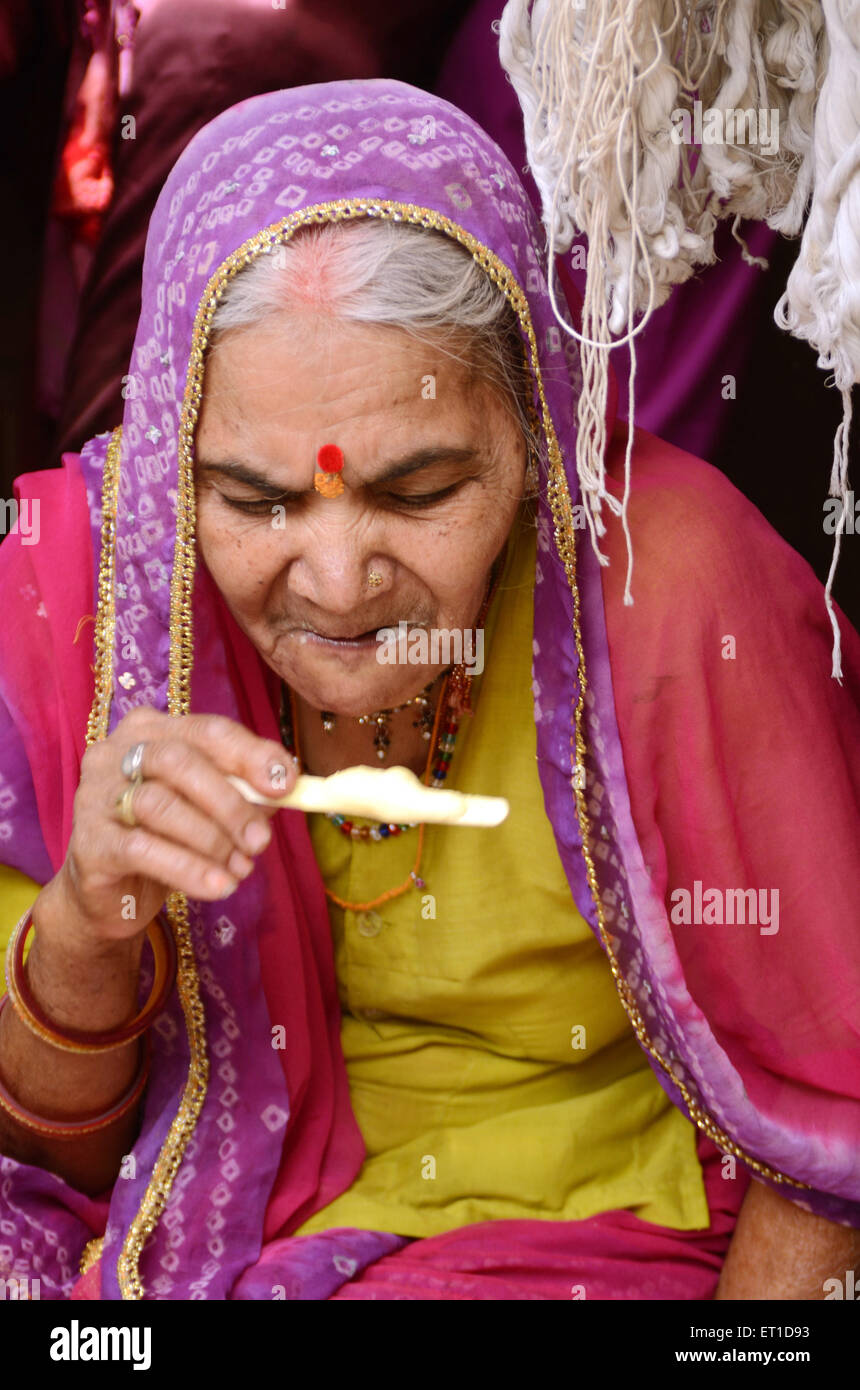 Una anciana disfrutando de ice caramelo en carretera en procesión de Ramnavami Jodhpur Rajastán India No, señor Foto de stock