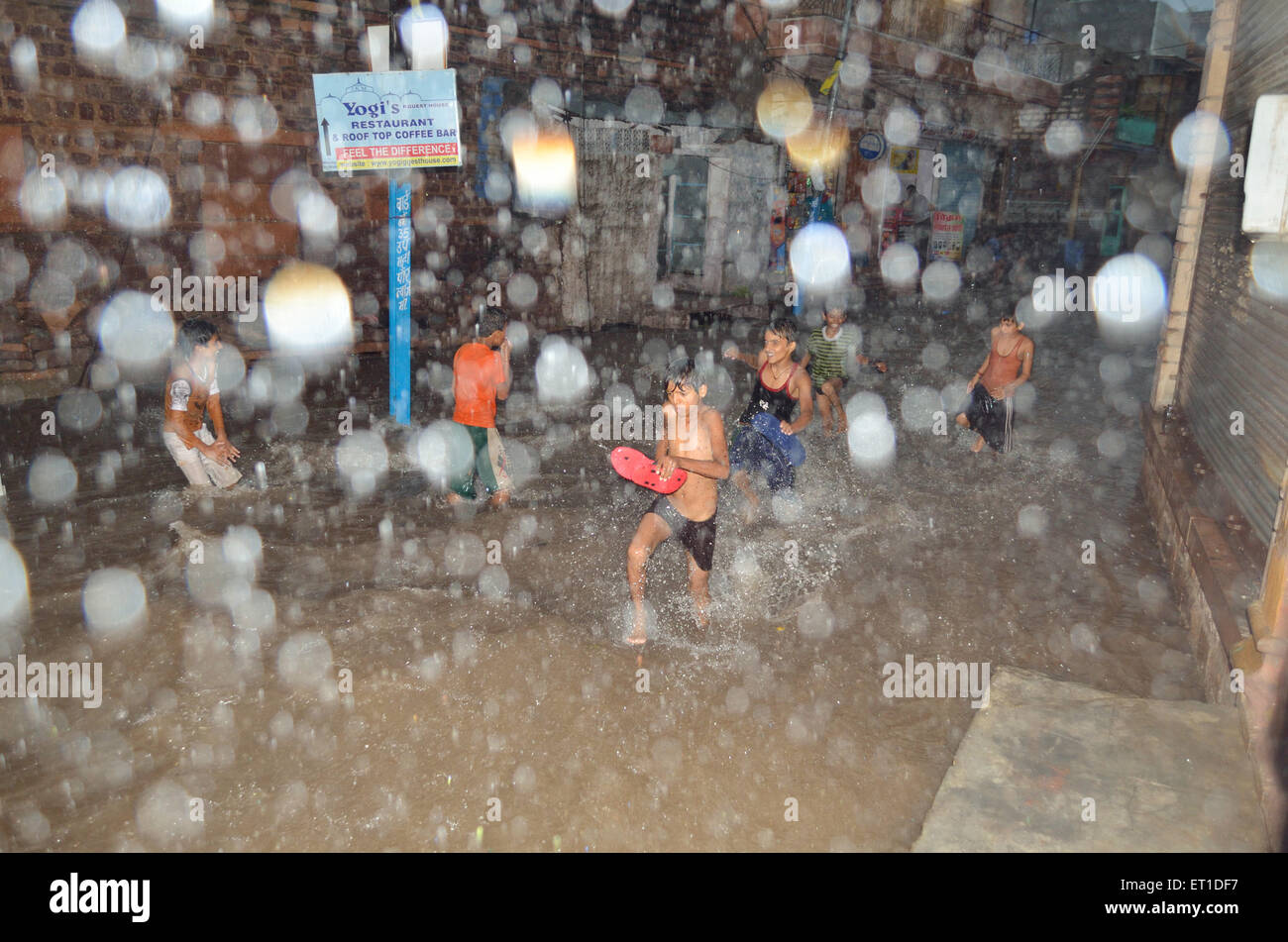 Los niños intentan escapar de las inundaciones de agua en la carretera de monzón Mohalla Makrana Jodhpur Rajastán India Asia Foto de stock