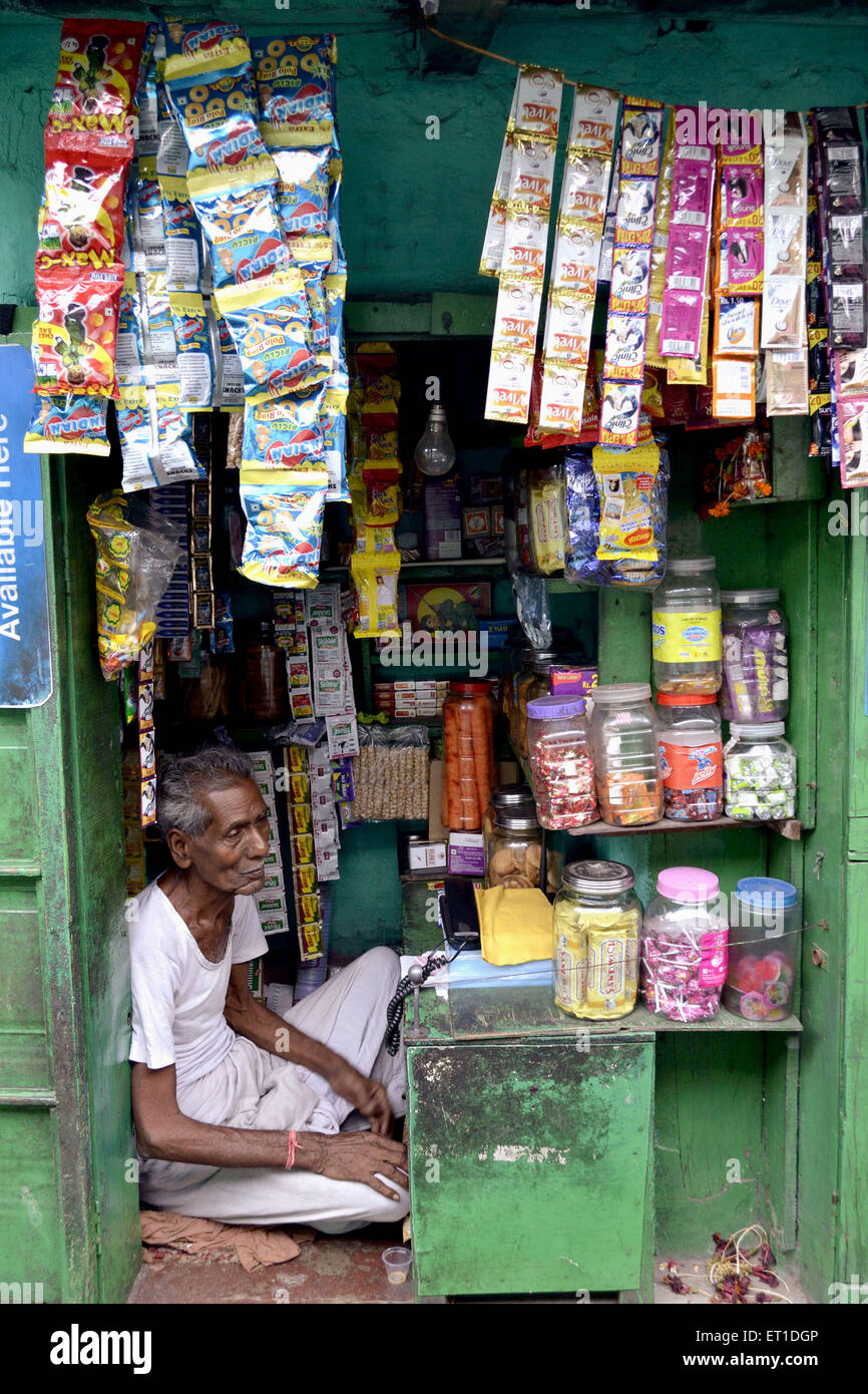 Un anciano sentado su pequeña tienda en cabina callejuela Kolkata India Asia Foto de stock
