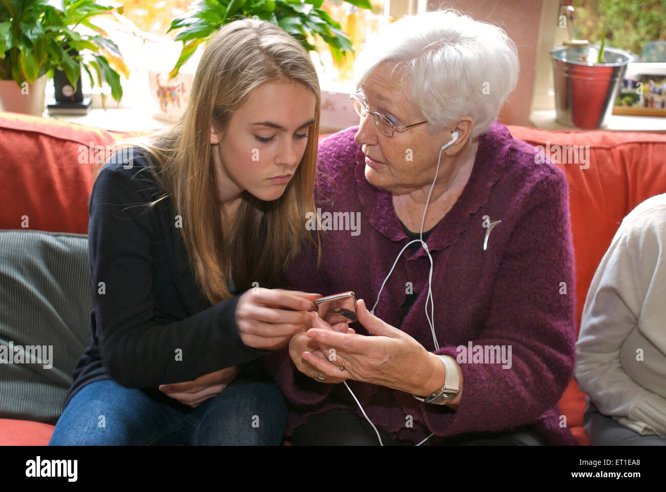 Abuela pidiendo su nieta acerca de cómo utilizar un i-pod y escuchar música porque ella no entiende Foto de stock
