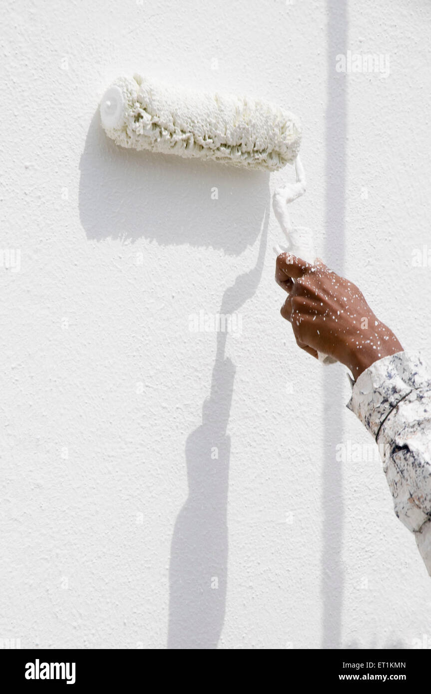 Hombre de pintar una pared con rodillo de pintura Foto de stock