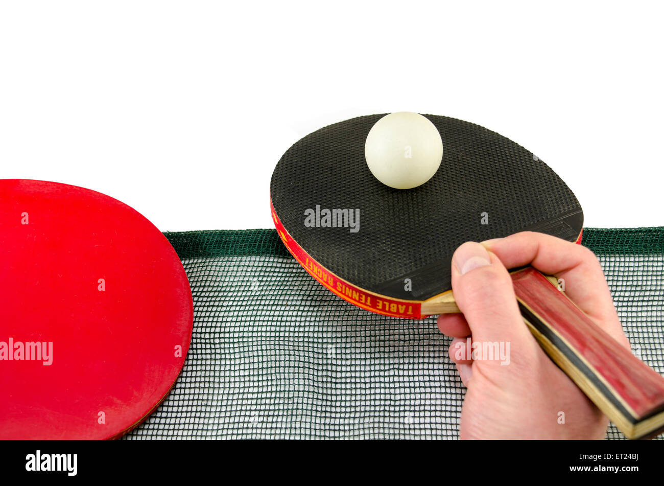 Hombre mano sosteniendo una raqueta de ping pong y una pelota de tenis de mesa por encima de una red, aislado en blanco Foto de stock