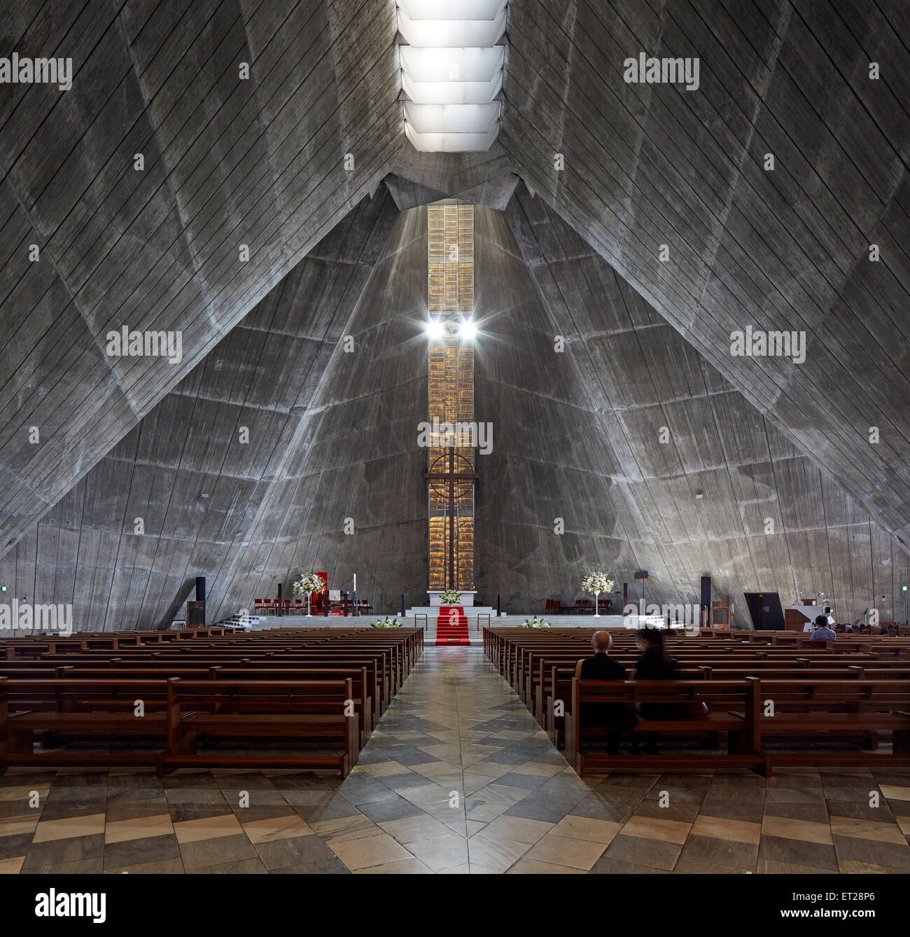Vista interior hacia alterar con figuras en primer plano. La Catedral de Santa María, en Tokio, Japón. Arquitecto: Kenzo Tange Tange/Assoc Foto de stock