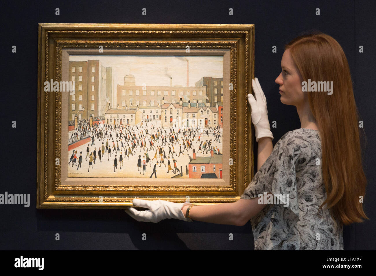 Un empleado de Christie's posa con la L.S. Lowry pintura 'ir a trabajar, estimar GBP 700,000-1m. Vista previa de los elementos destacados de la Christie's moderno Noche de Arte británico e irlandés la venta el 25 de junio de 2015 en Londres. Foto de stock