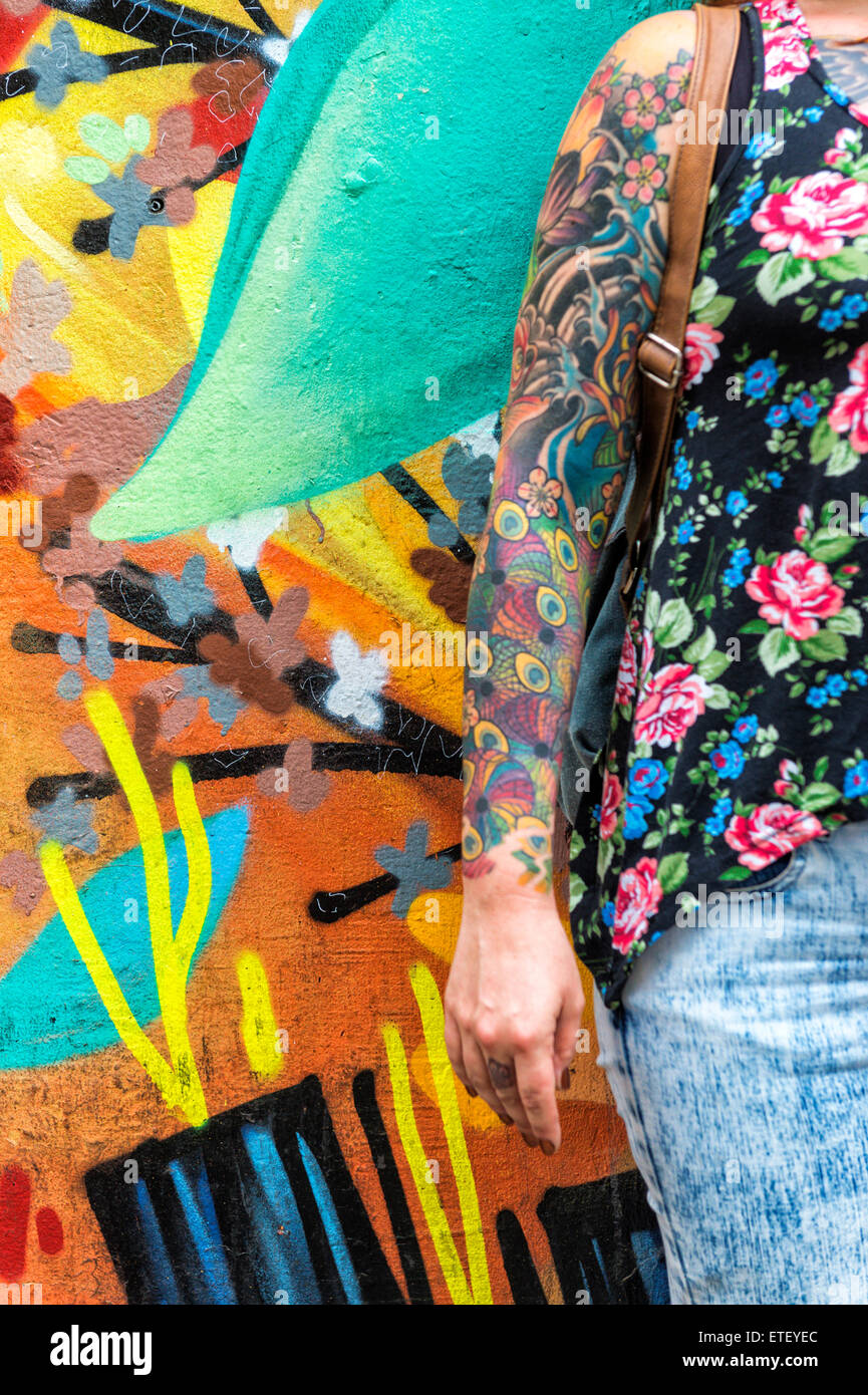 Mujer tatuada en frente una pared cubierta de graffiti, Barrio Bellavista, Santiago, Chile. Foto de stock
