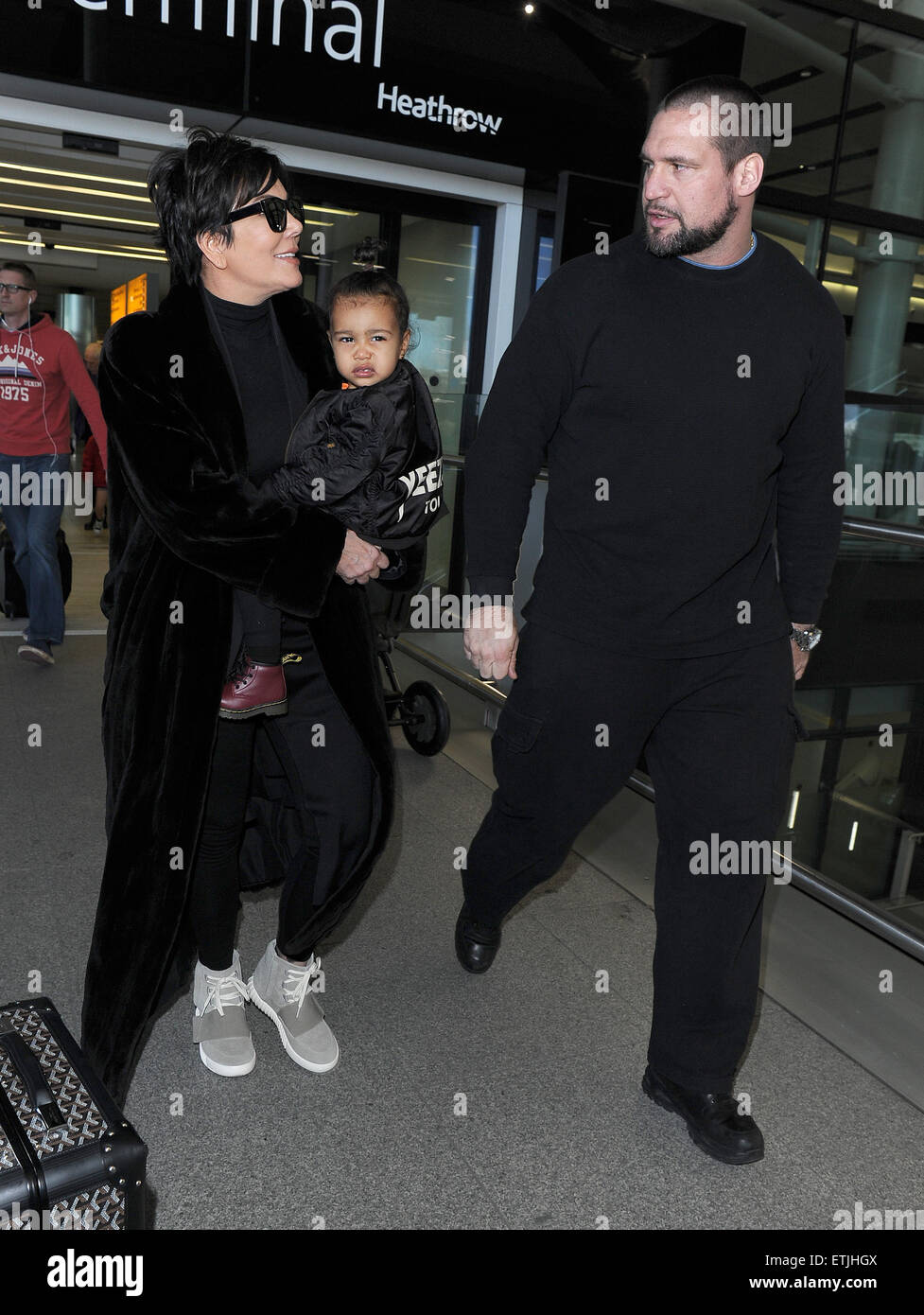Kris Jenner, vistiendo un par de Kanye West Yeezy Originales Adidas x 750  Boost, llega al aeropuerto de Heathrow llevando bebé North West, quien  llevaba una chaqueta de bombardero Yeezus Tour' en