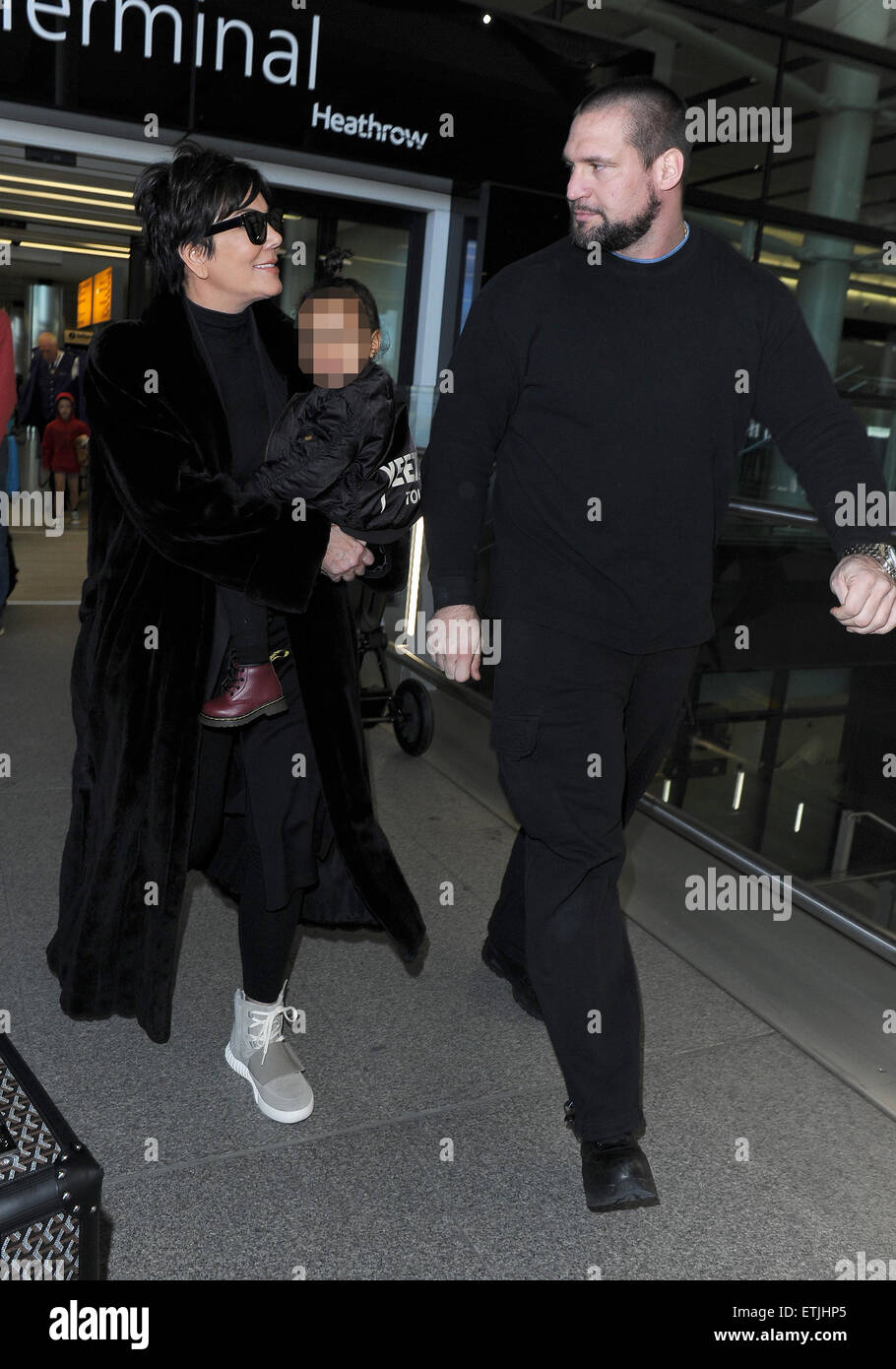 Kris Jenner, vistiendo un par de Kanye West Yeezy Originales Adidas x 750  Boost, llega al aeropuerto de Heathrow llevando bebé North West, quien  llevaba una chaqueta de bombardero Yeezus Tour' en