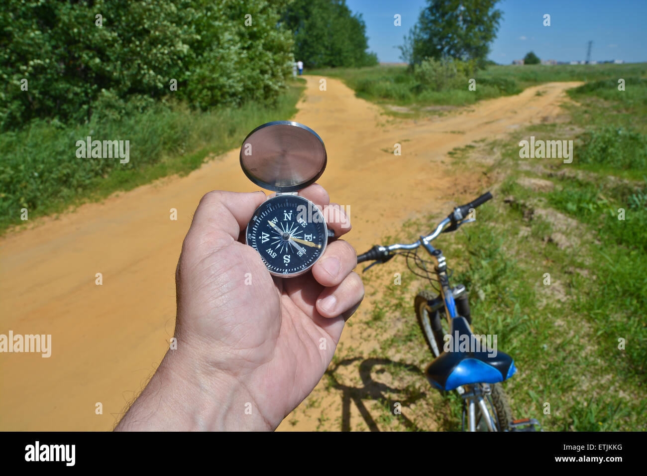 Con una brújula y horquilla delantera de una bicicleta. Orientación durante un paseo en bicicleta en las zonas rurales. Foto de stock