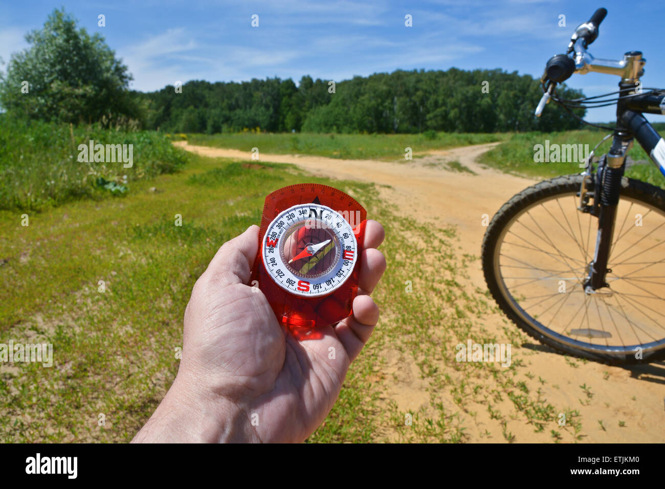 Con una brújula y horquilla delantera de una bicicleta. Orientación durante un paseo en bicicleta en las zonas rurales. Foto de stock