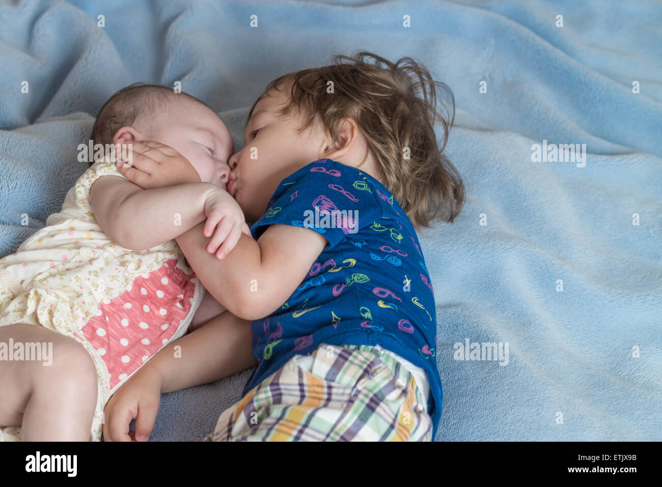 Un niño de 2 años, y su hermana recién nacida acostado en una cama. Foto de stock
