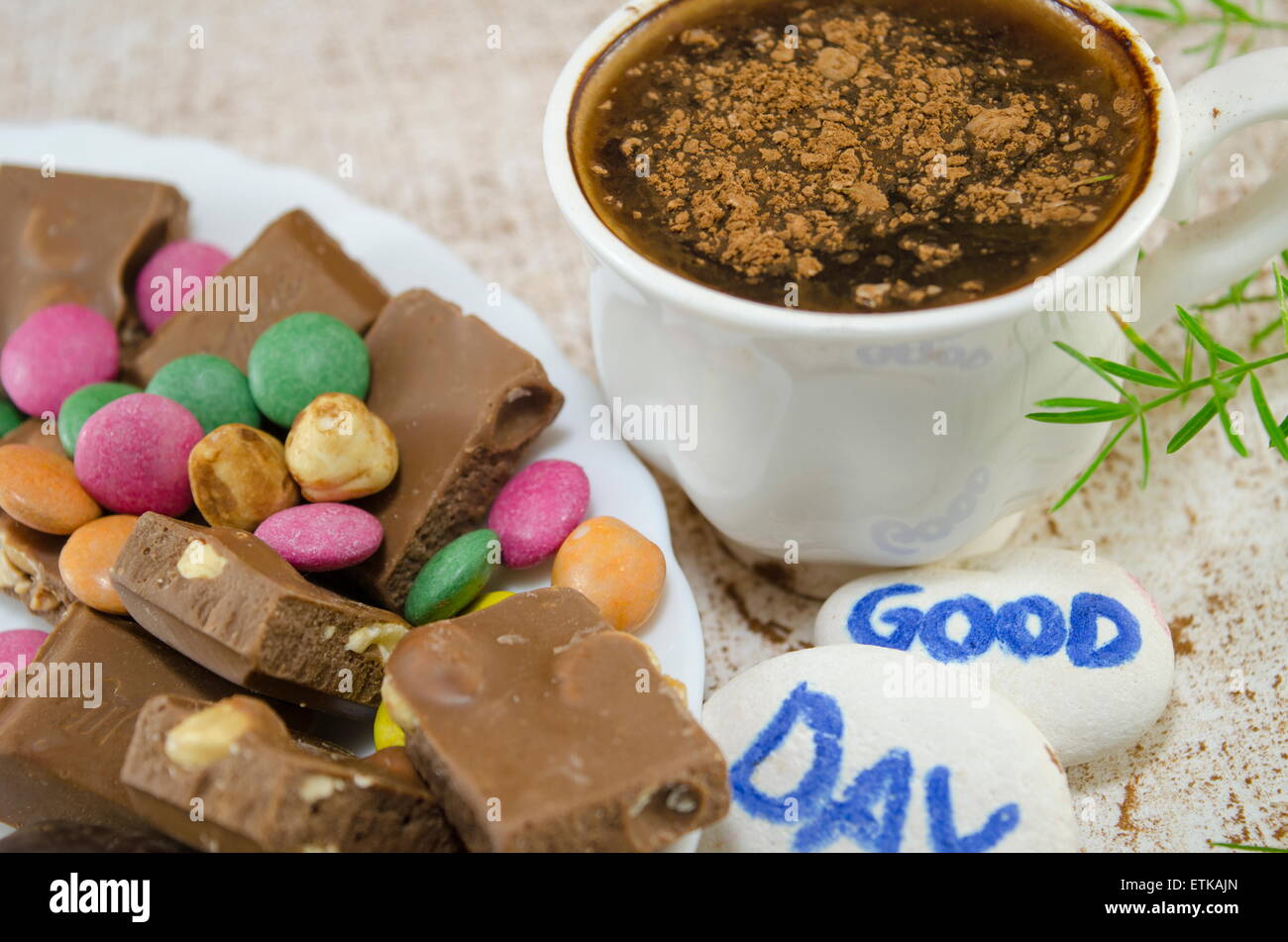 Café Chocolate con bombones y un "buen día" mensaje escrito sobre piedritas Foto de stock