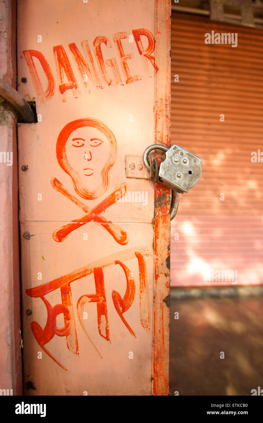El peligro y la Calavera y huesos cruzados pintado sobre un armario eléctrico. En Hindi también. La India Foto de stock